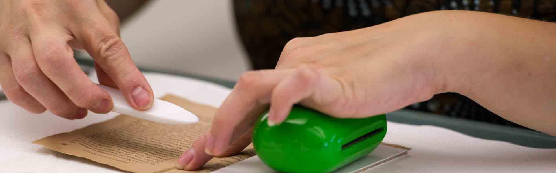 Conservator mending old book with bone folder.